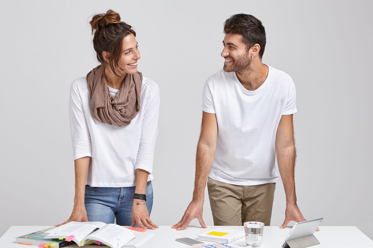 Uomo e donna che si sorridono in piedi dietro a una scrivania