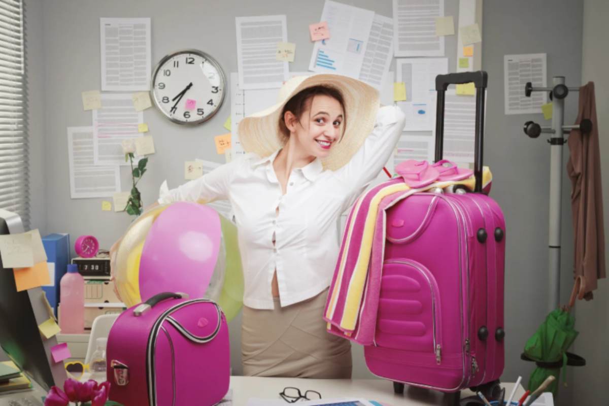 donna felice con le valigie sopra la scrivania dell'ufficio