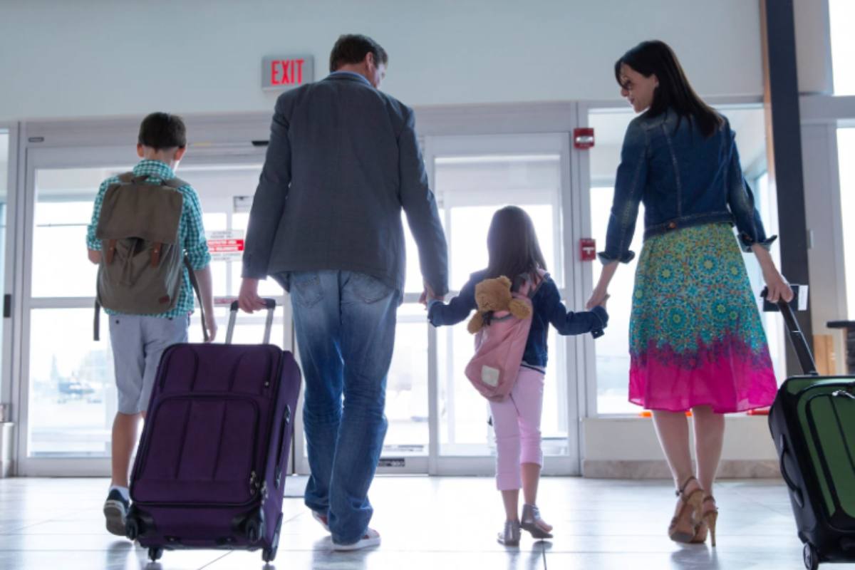 coppia con bambini in aeroporto con le valigie