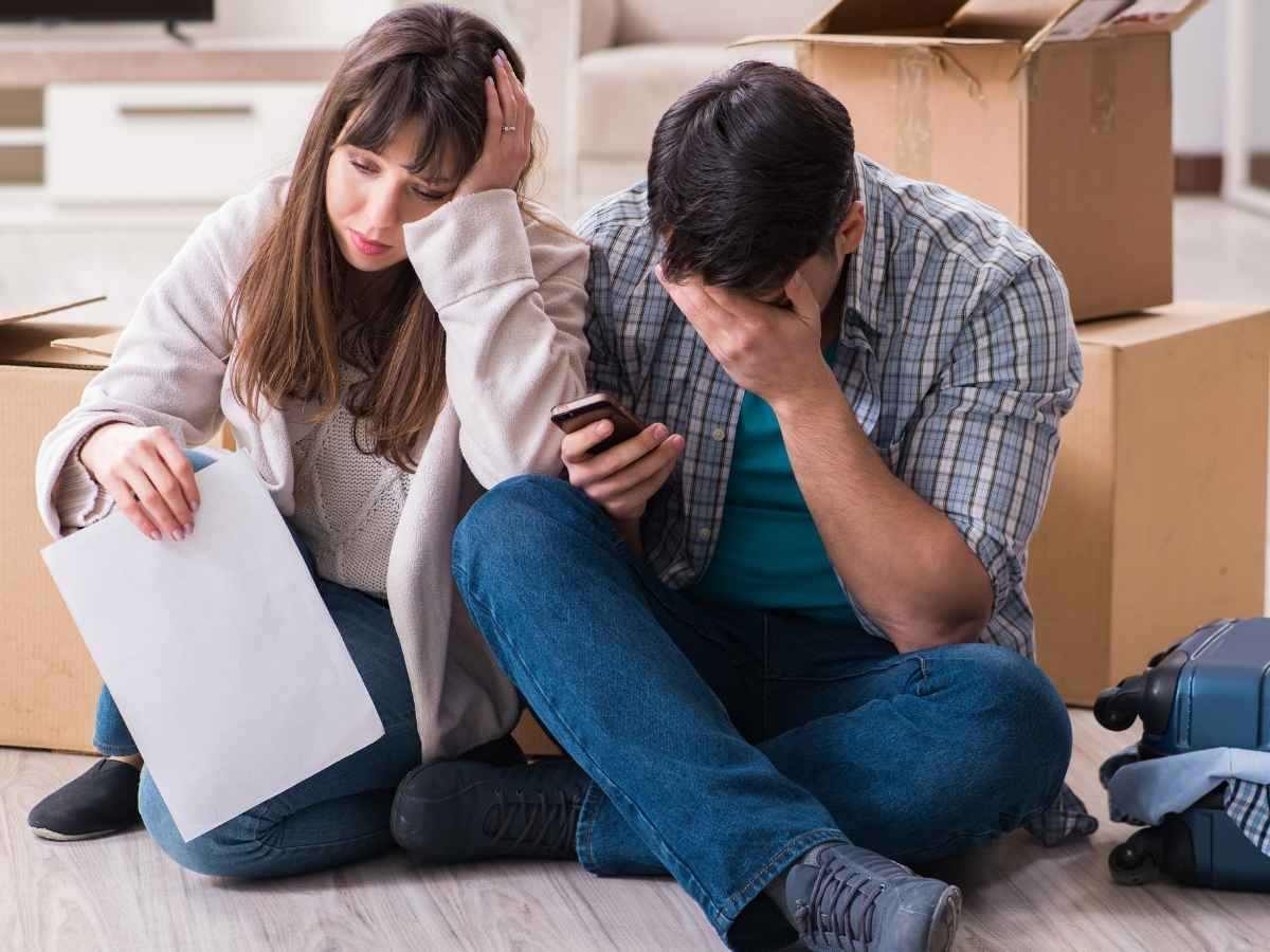 Coppia in crisi seduta sul pavimento dell'appartamento