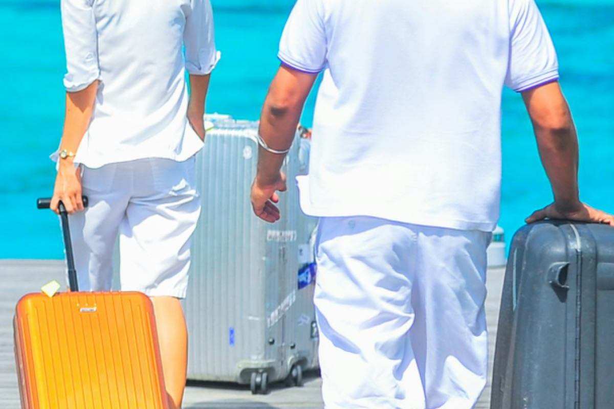 turisti che camminano trasportando le valigie