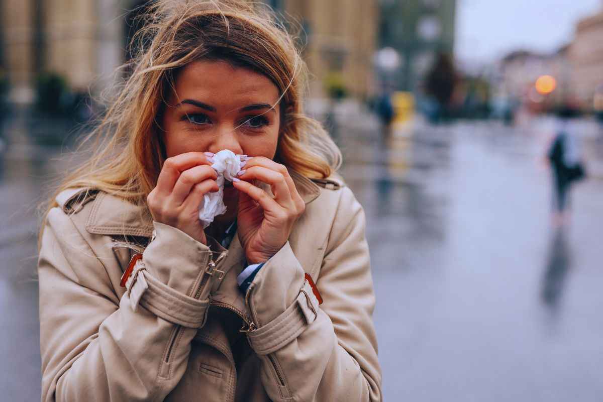 Donna raffreddata che si muove in un contesto cittadino freddo e piovoso