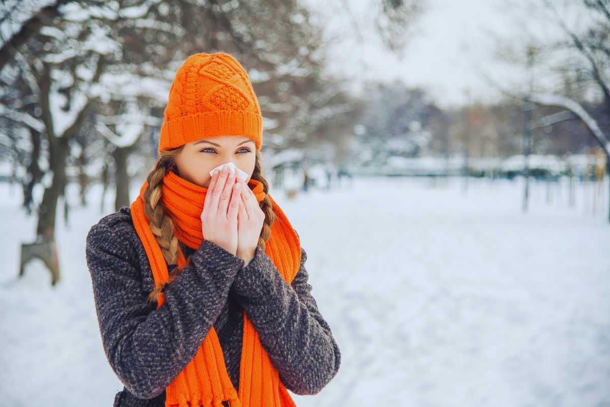 Ragazza infreddolita passeggia in un bosco innevato
