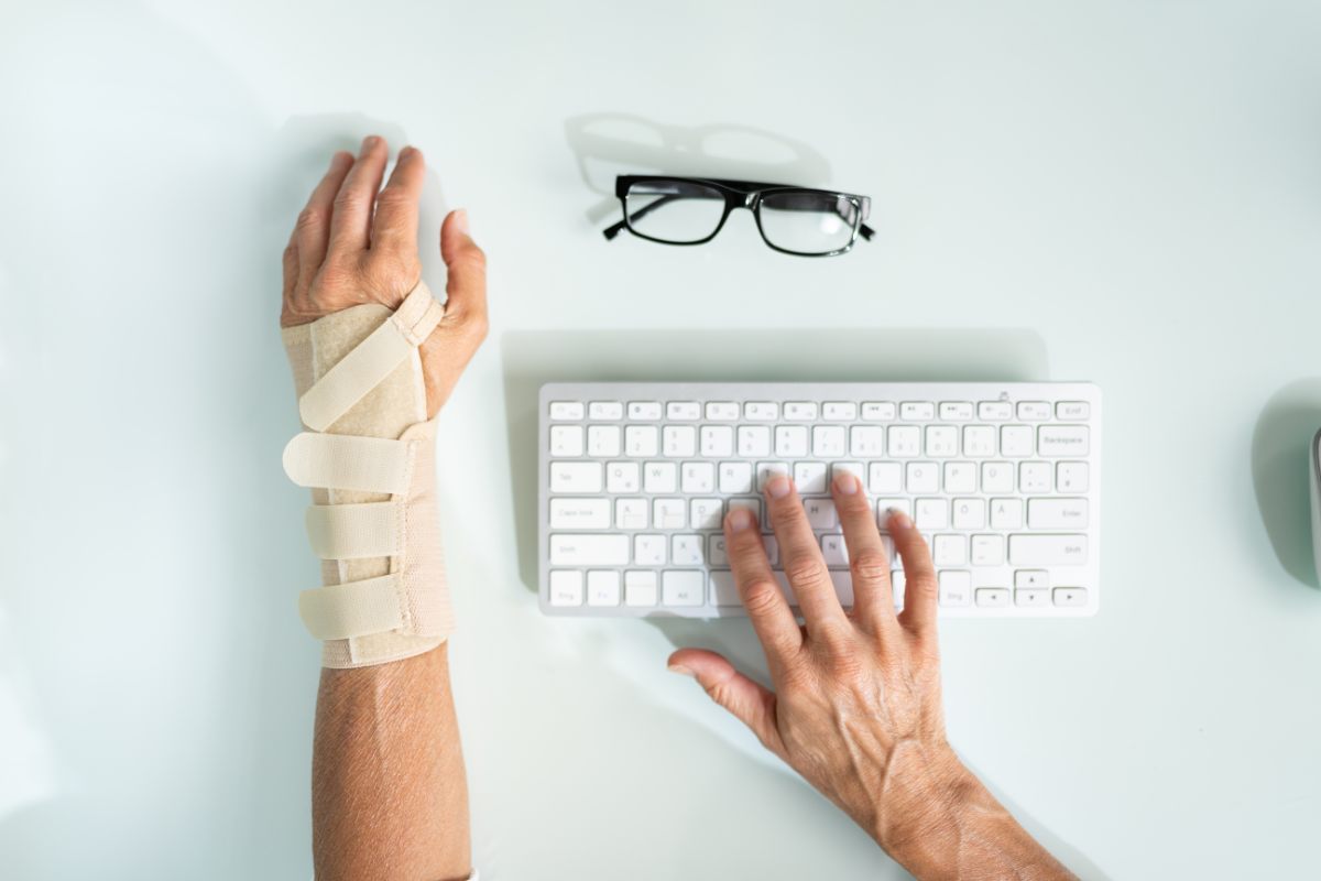 Persona che lavora al pc con il polso fasciato