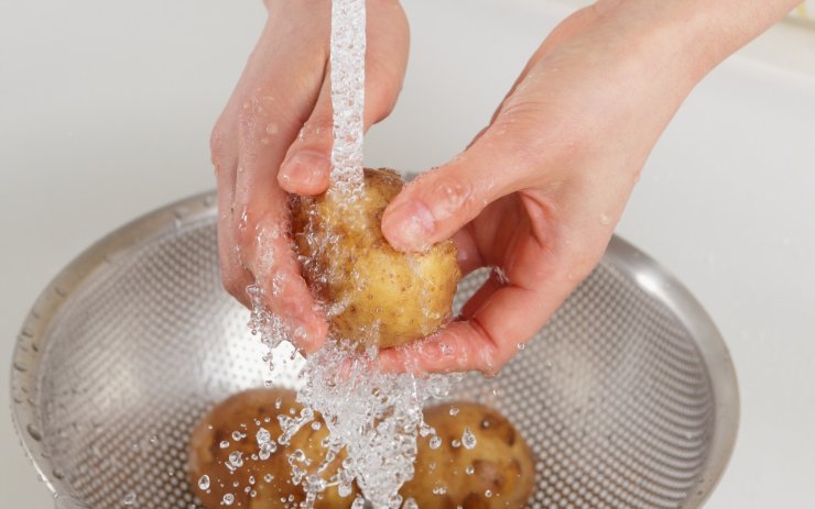 Persona che lava le patate sotto l'acqua