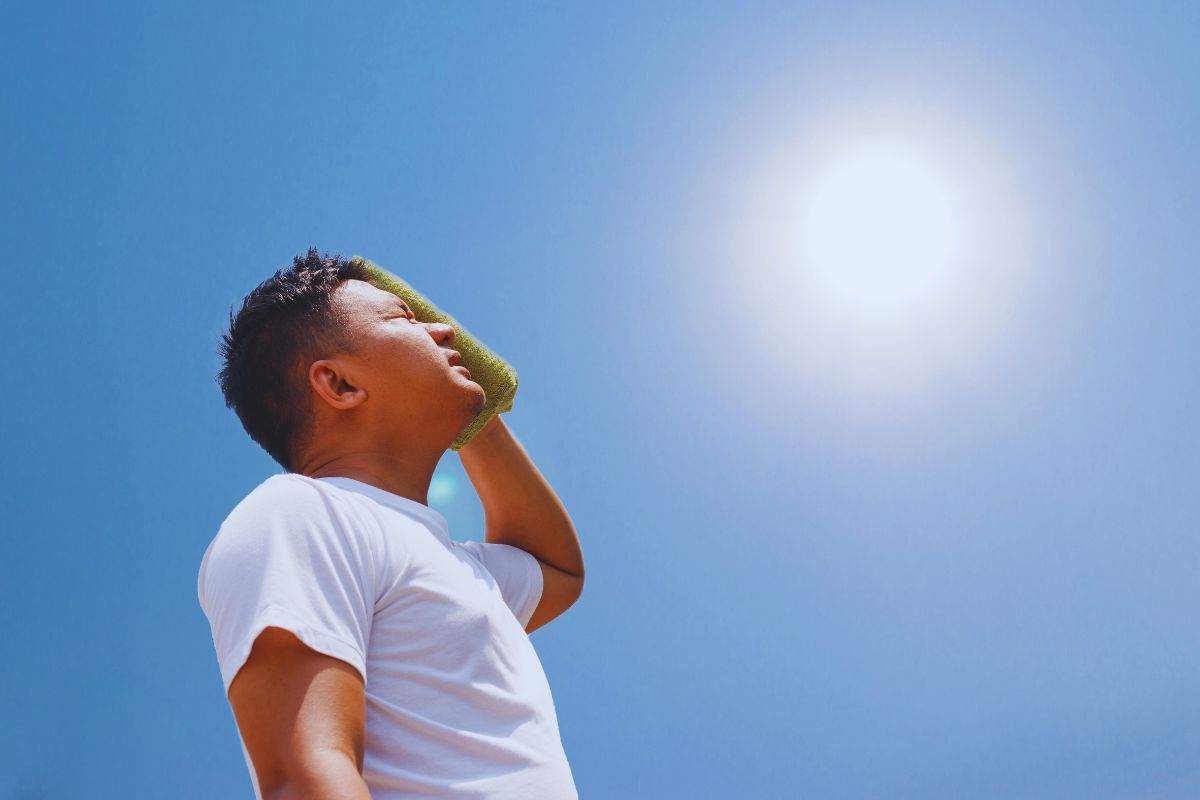 Uomo sotto il sole che si asciuga il sudore con una tovaglia