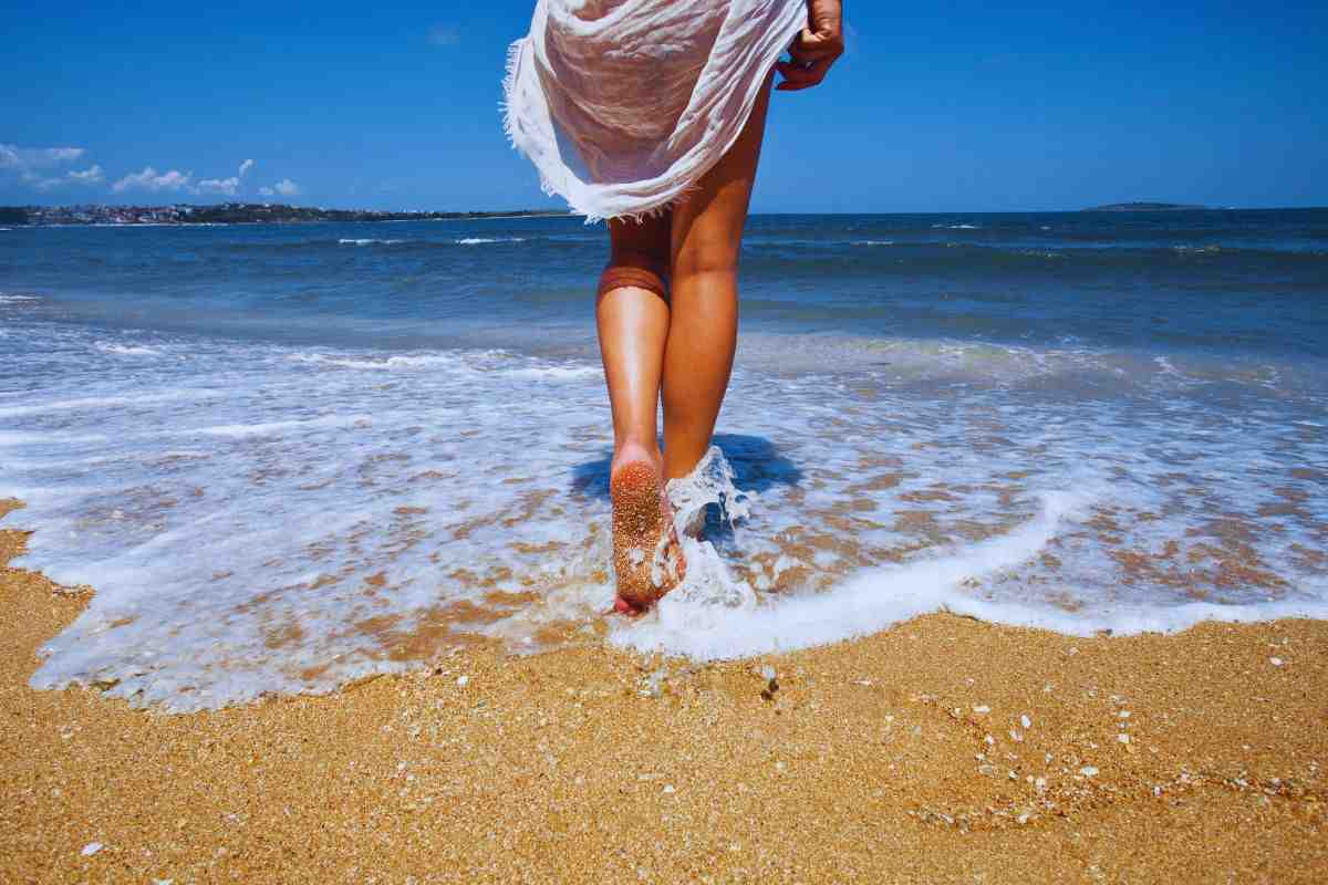 Donna che bagna i piedi a riva