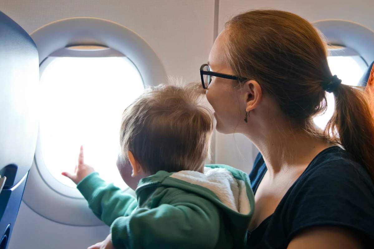 Bimbo in braccio alla mamma che guarda dall'oblò dell'aereo