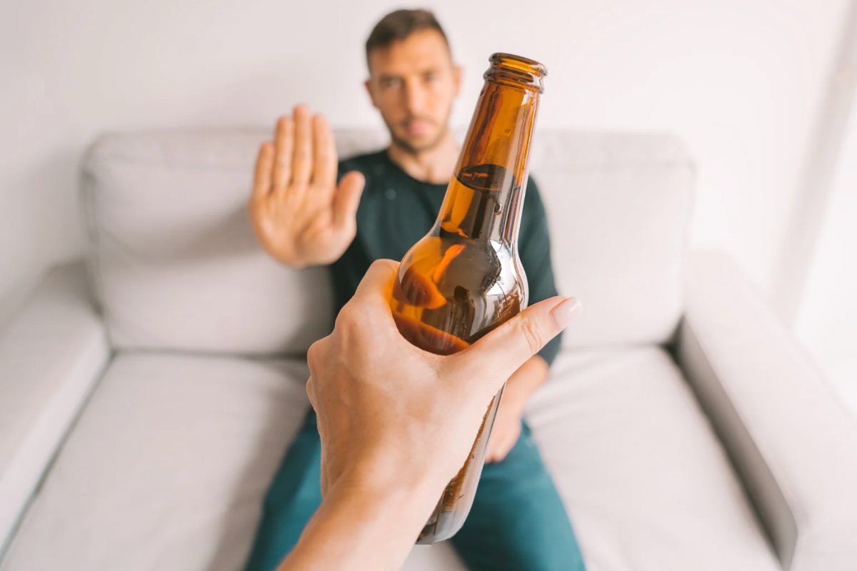 Uomo che stende una mano per rifiutare bottiglia di birra
