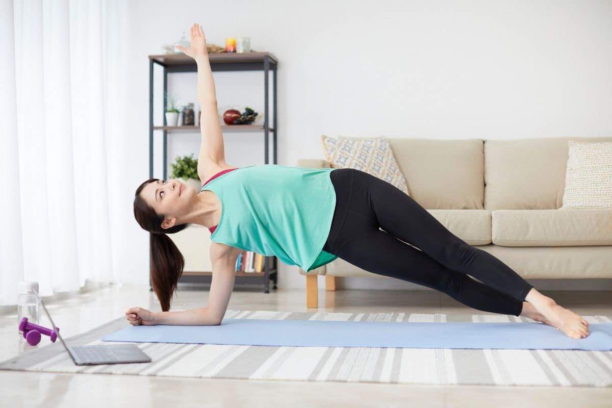 Donna che fa un plank laterale in casa