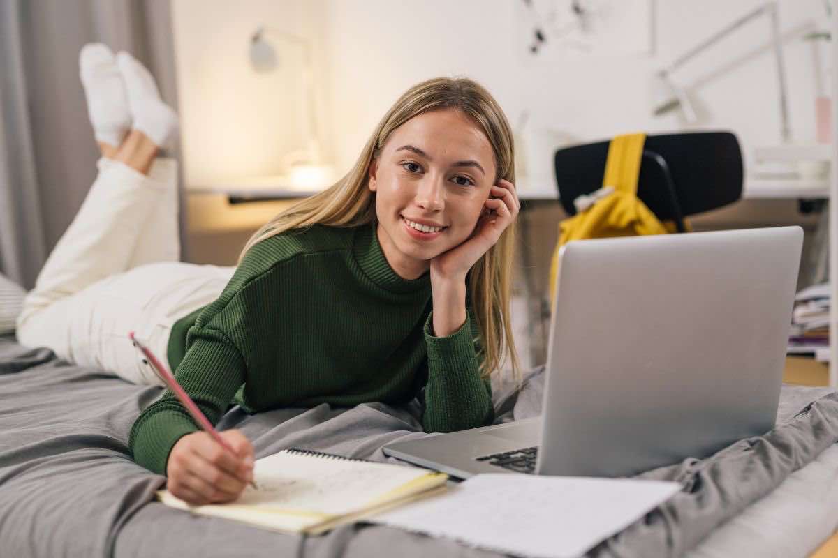 Studentessa sul letto con computer davanti