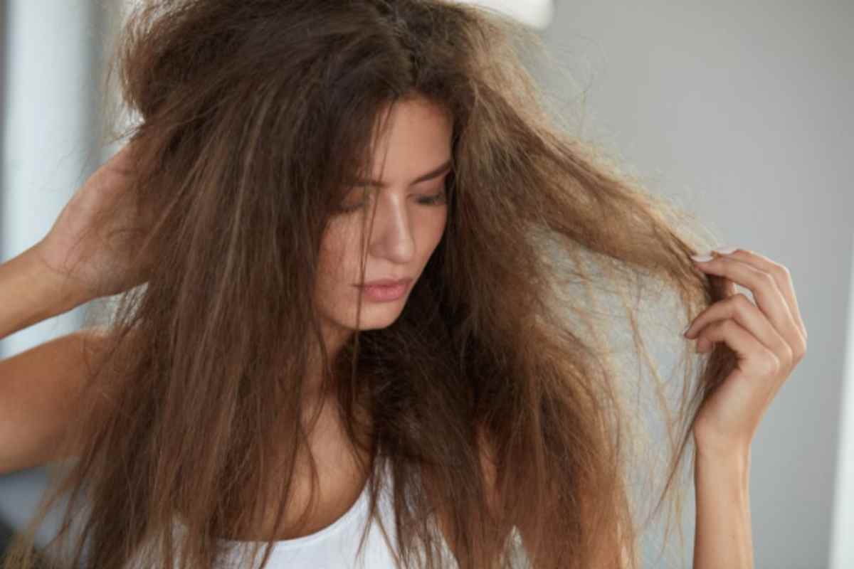 Ragazza che controlla i capelli rovinati dal mare