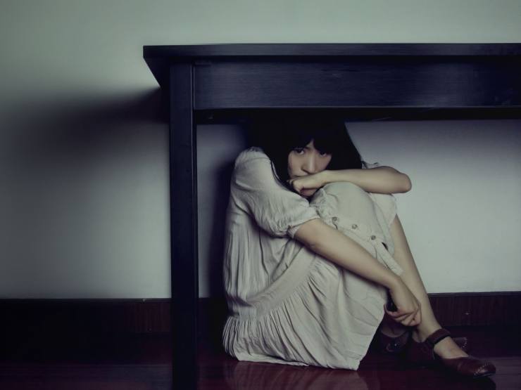 ragazza spaventata sotto il tavolo 