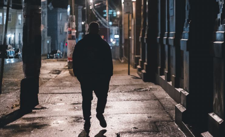 Uomo che cammina da solo in città durante la notte