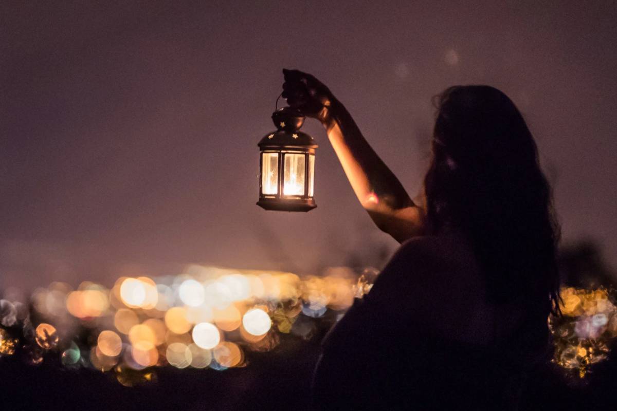 Donna che tiene lanterna in mano nella notte