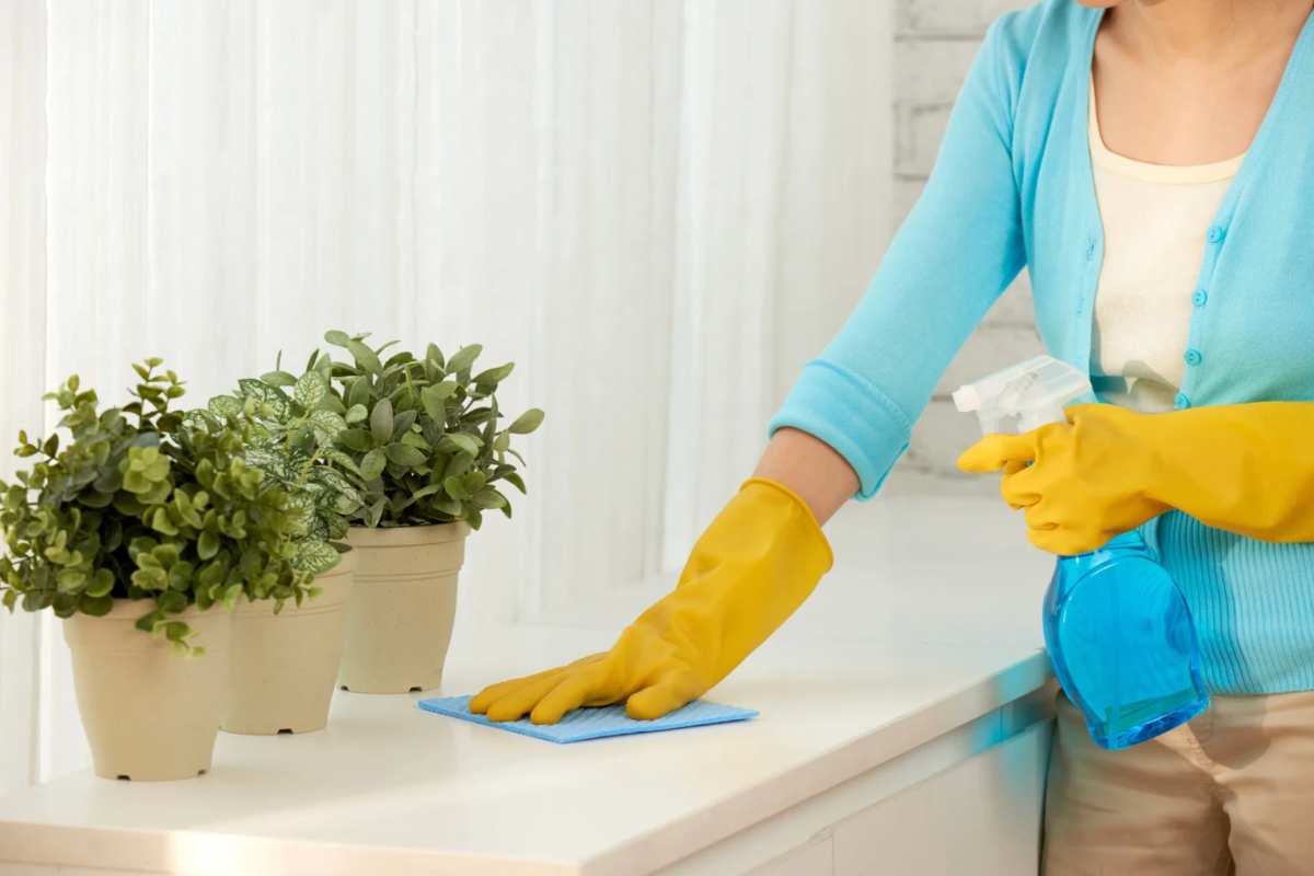 Donna che pulisce un mobile con panno e prodotto spray