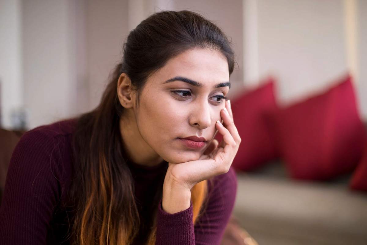 Donna triste che si sostiene la testa con la mano