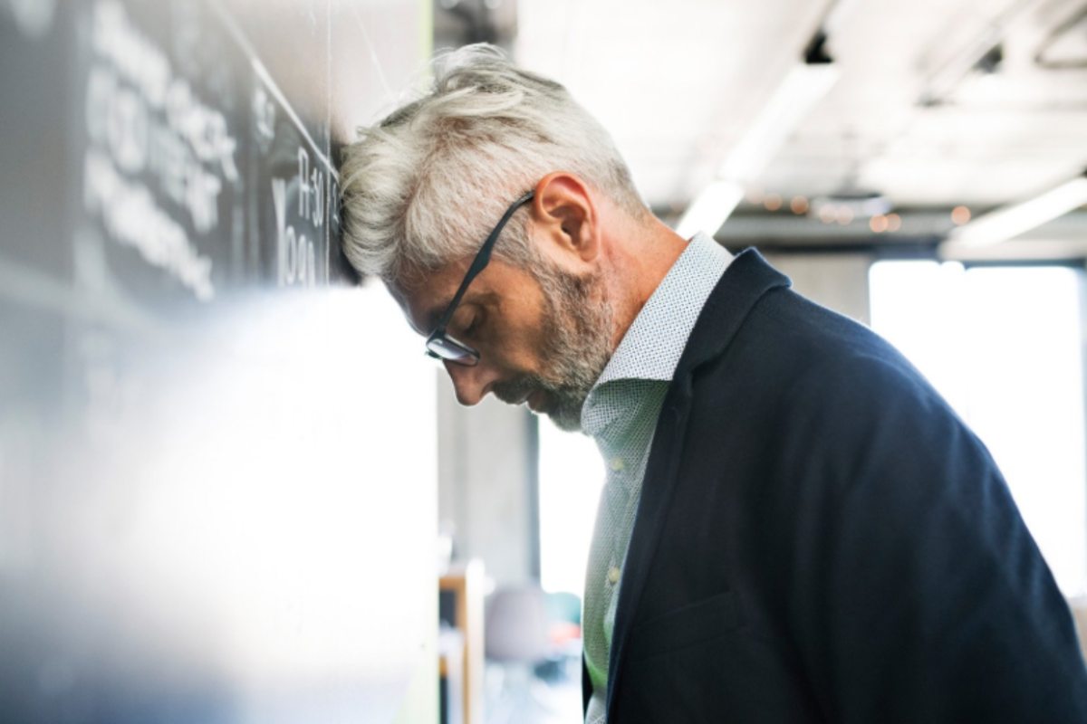 uomo anziano con la fronte contro il muro