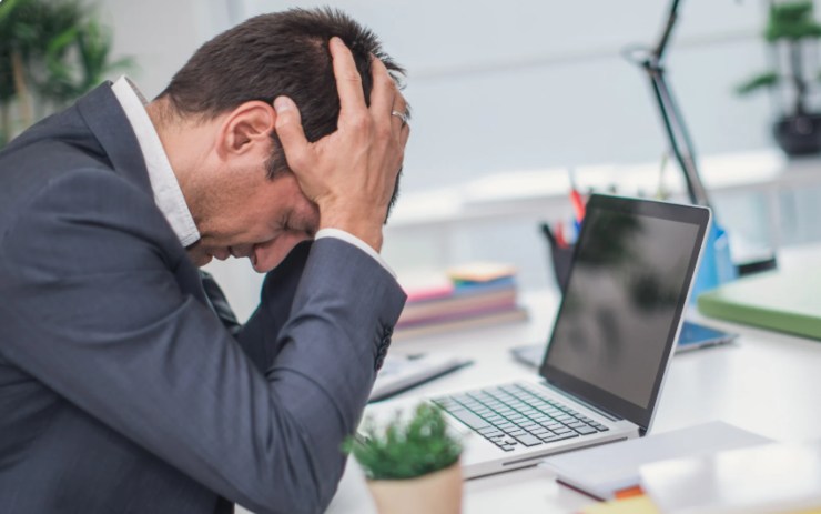 uomo alla scrivania disperato con la testa tra le mani