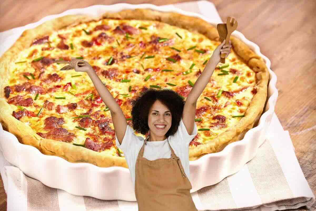 Donna esulta con grembiule, dietro di lei torta salata