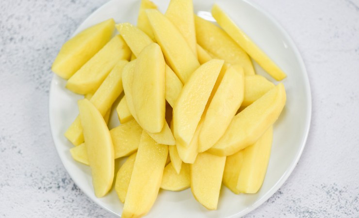 Piatto con patate crude tagliate a spicchi