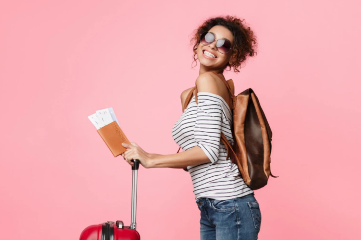 donna felice con passaporto trolley e occhiali da sole