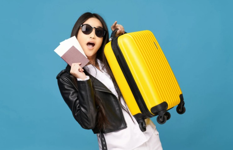 donna con in mano il passaporto mentre sollevo un trolley giallo