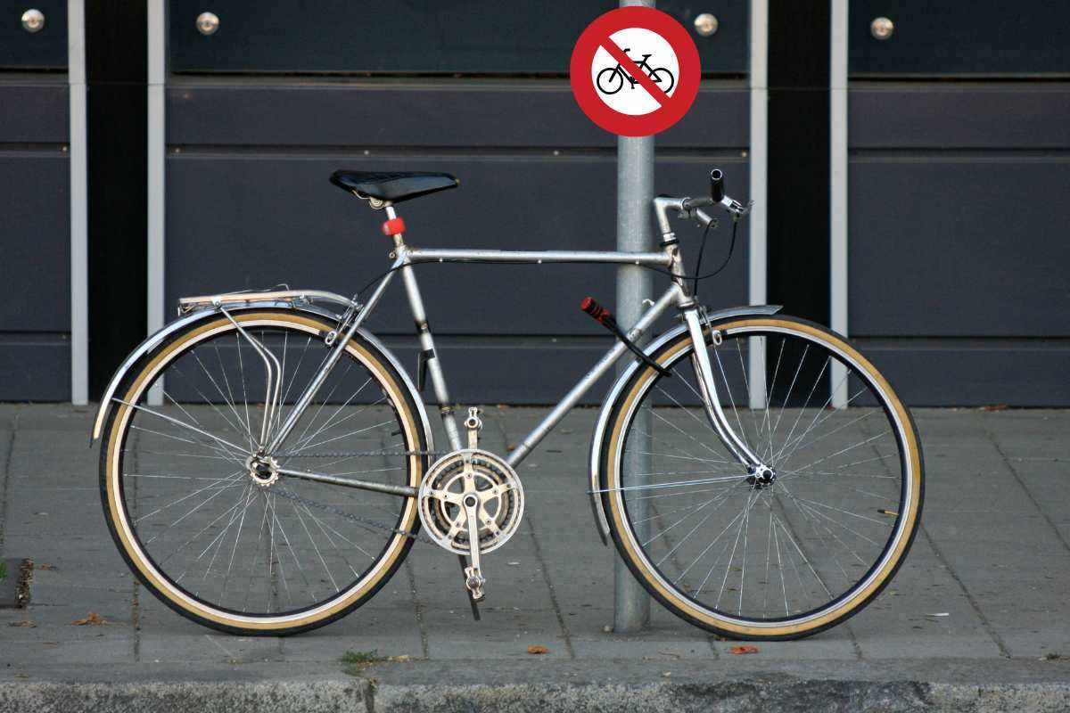 bici legata al palo e segnale di divieto