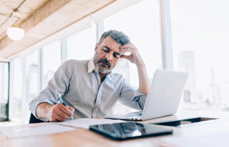 uomo davanti al computer che scrive su un foglio