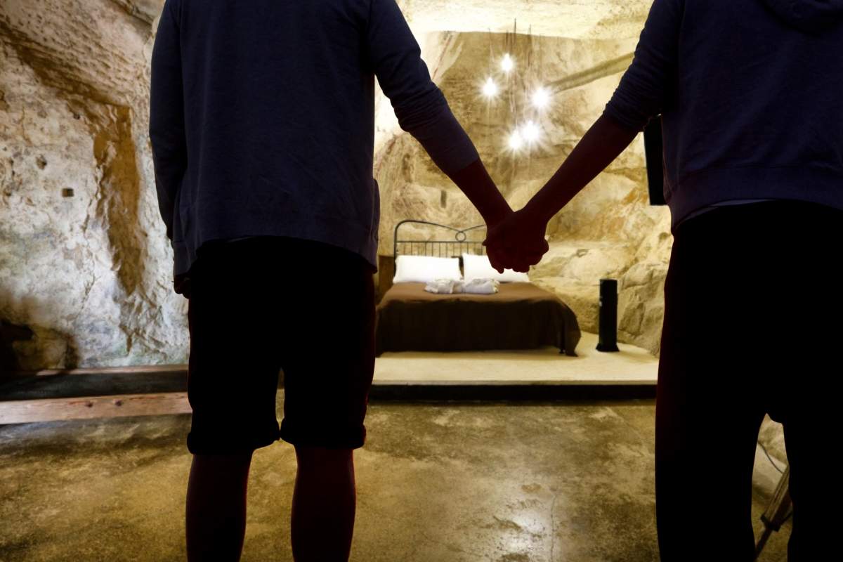 camera da letto di un'alloggio di Chez Les Grottes e coppia in primo piano che si tiene per mano mentre la guarda