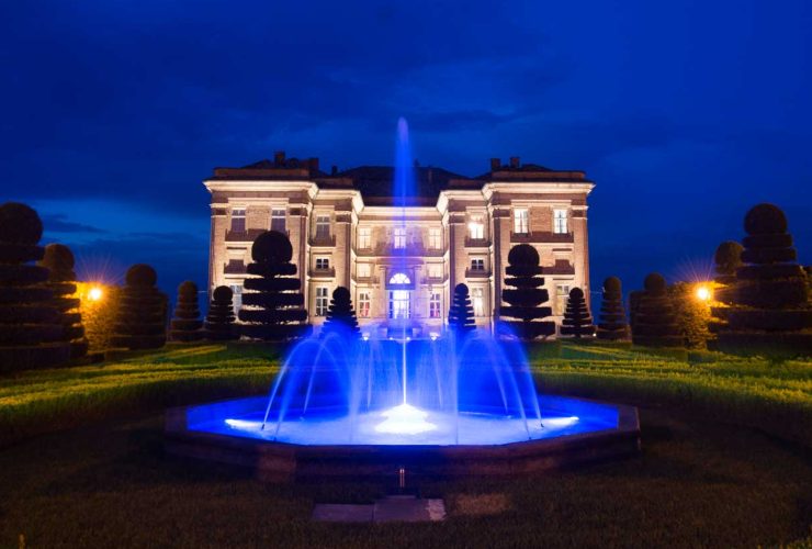 Castello di Guarene visto da fuori con fontana illuminata di blu. Cielo notturno