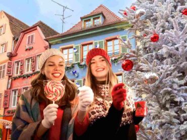 sfondo città europea a Natale e ragazze che passeggiano mangiando dolciumi