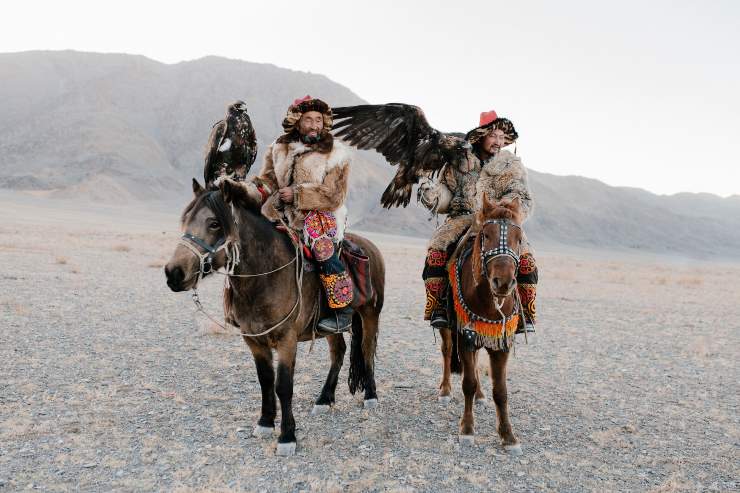 Cacciatori mongoli in sella ai cavalli con un'aquila sul braccio