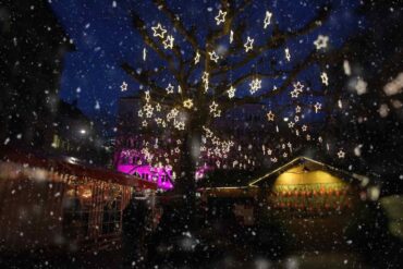 Mercatini di Natale a Zurigo: piazza con luci a forma di stelle e neve che scende