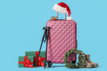 Valigia con cappellino di babbo natale sopra e pacchi regalo a fianco