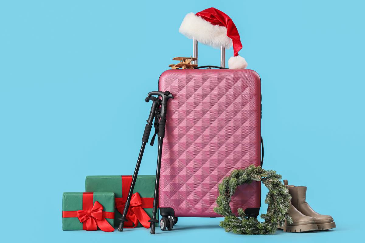 Valigia con cappellino di babbo natale sopra e pacchi regalo a fianco