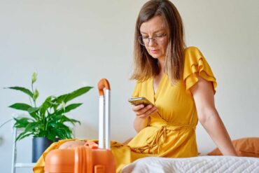 Donna con valigia e cellulare in mano