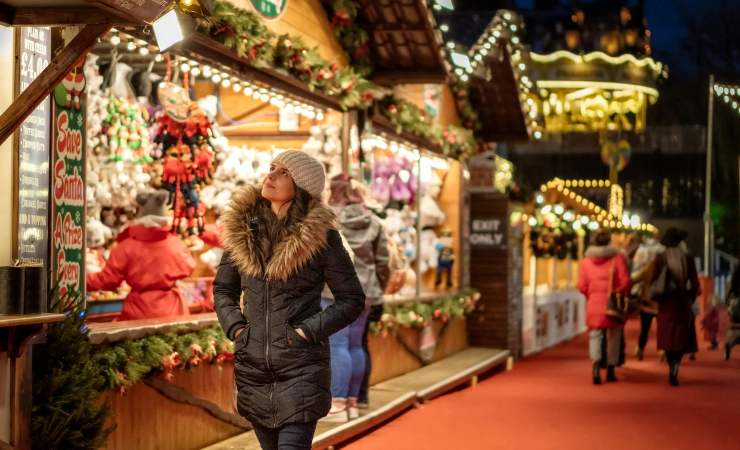 Donna che cammina tra bancarelle di Natale