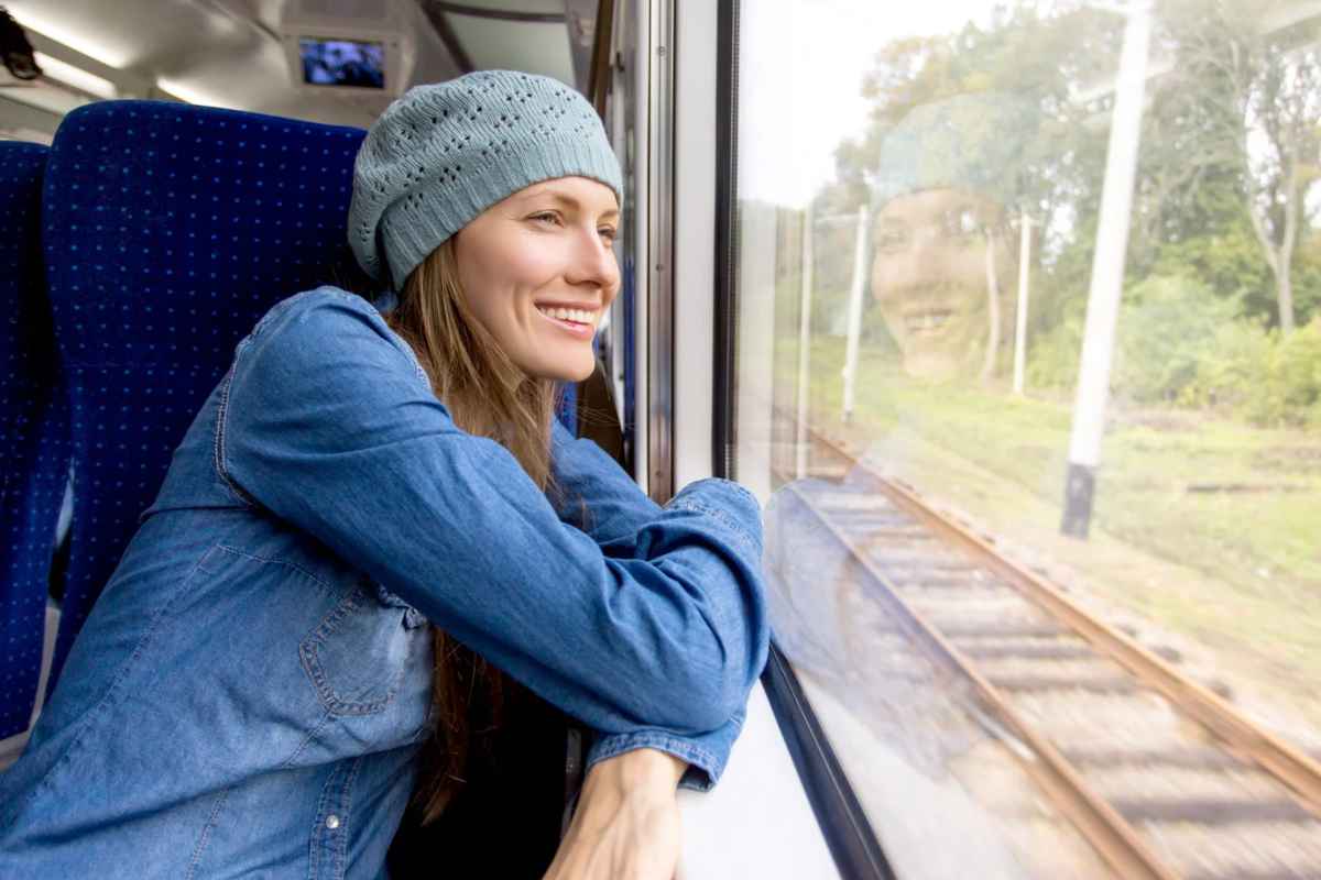 Donna sorridente che guarda fuori dal finestrino del treno