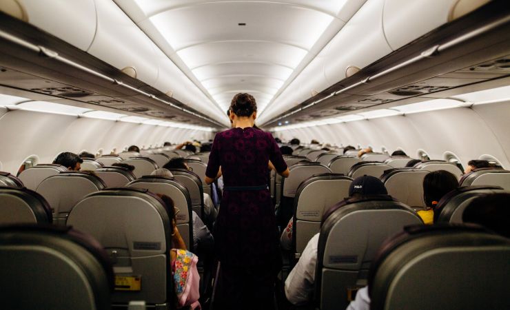 Interno di un aereo con persone sedute e una in piedi