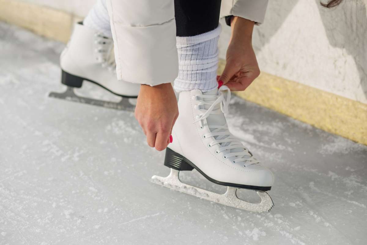 Persona sui pattini che si abbassa per allacciarli