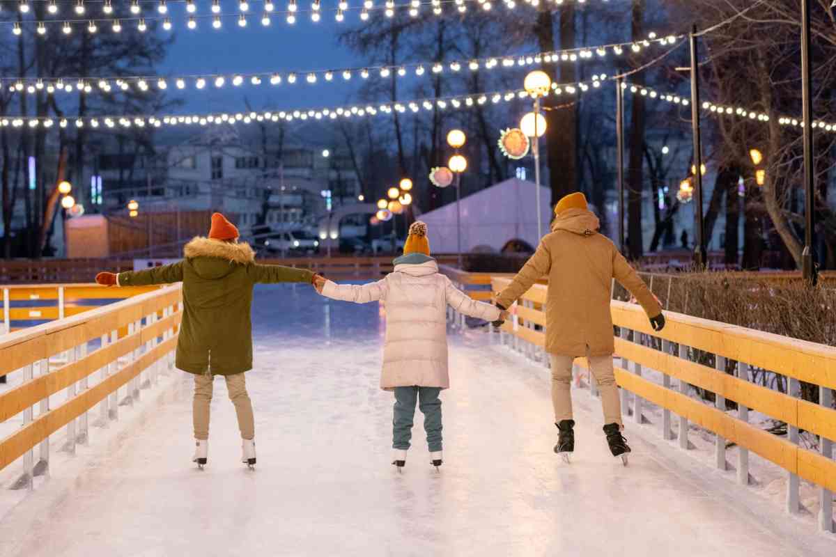 Tre bambini di spalle che pattinano sul ghiaccio