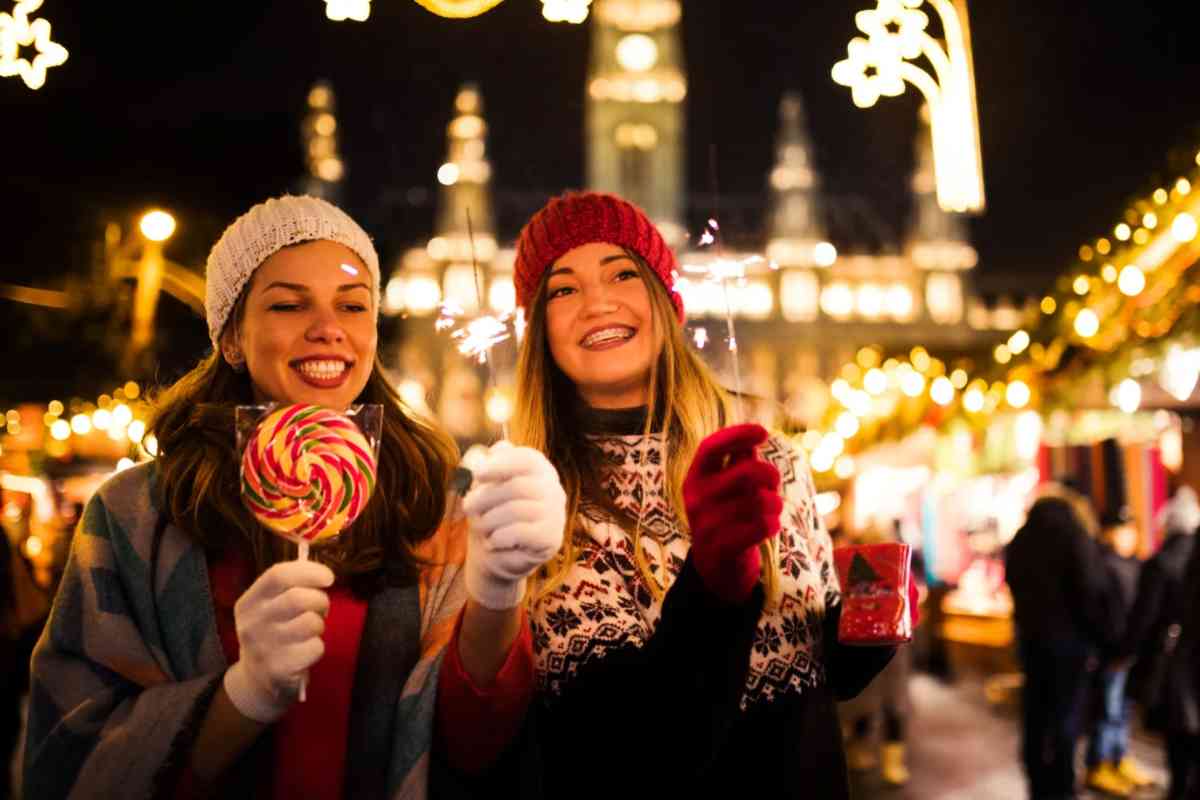 Due ragazze che mangiano dolci con luci alle spalle