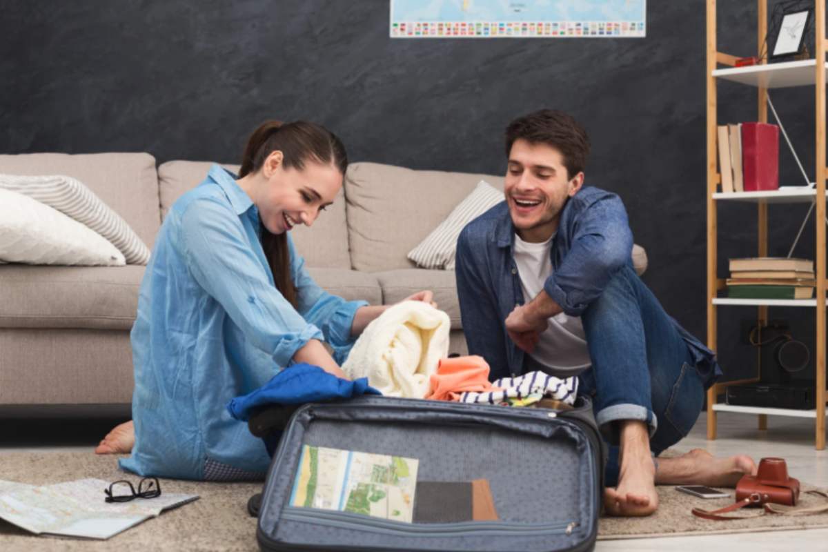 uomo e donna che sorridono mentre preparano la valigia