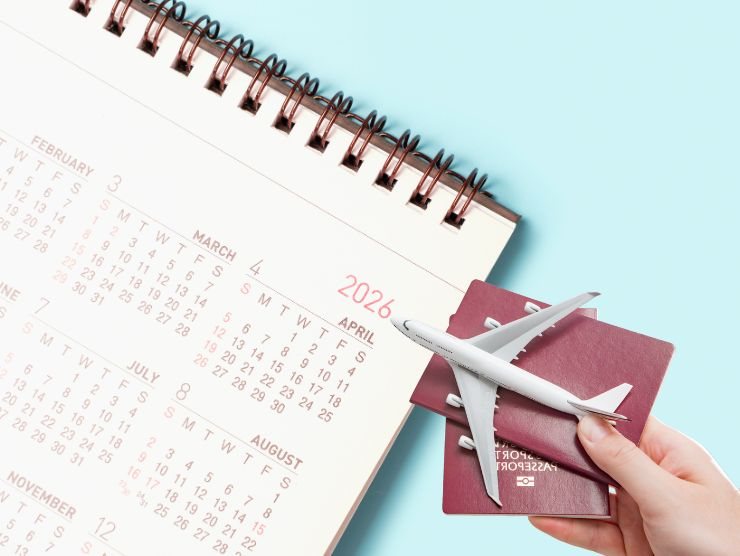 calendario 2026 e mano che mantiene passaporto e modellino di aereo