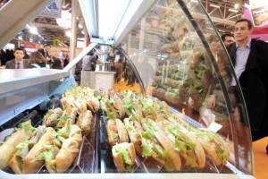 People stand near a stand of sandwiches